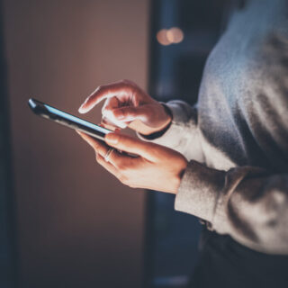 Young hipster girl using modern smartphone in hands.Horizontal, blurred background, bokeh effects.